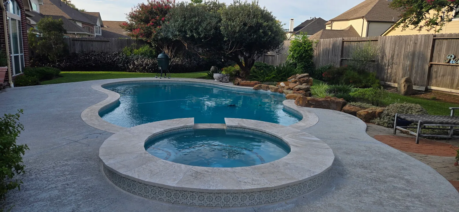 Freeform pool with a raised round spa and rock waterfall in a Houston-area backyard